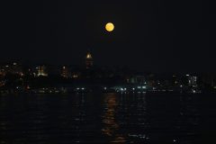 The full moon rises behind the Galata tower in Istanbul, Turkey, Wednesday, Aug. 30, 2023. The cosmic curtain rose Wednesday night with the second full moon of the month, the reason it is considered blue. It is dubbed a supermoon because it is closer to Earth than usual, appearing especially big and bright.(AP Photo/Khalil Hamra)